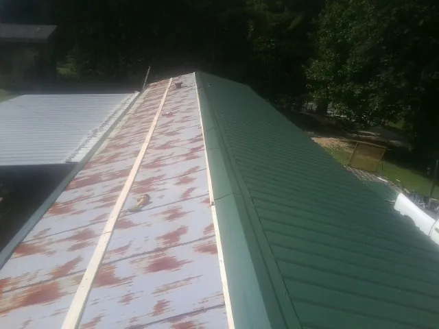 Old rusted panels beside newly installed green metal roofing — Wind Damage Roof Repair by Roofing Brothers in Danville