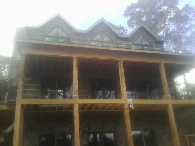 Dormers and porch framing on a large log home under construction — Roof Coating work by our crew in Danville